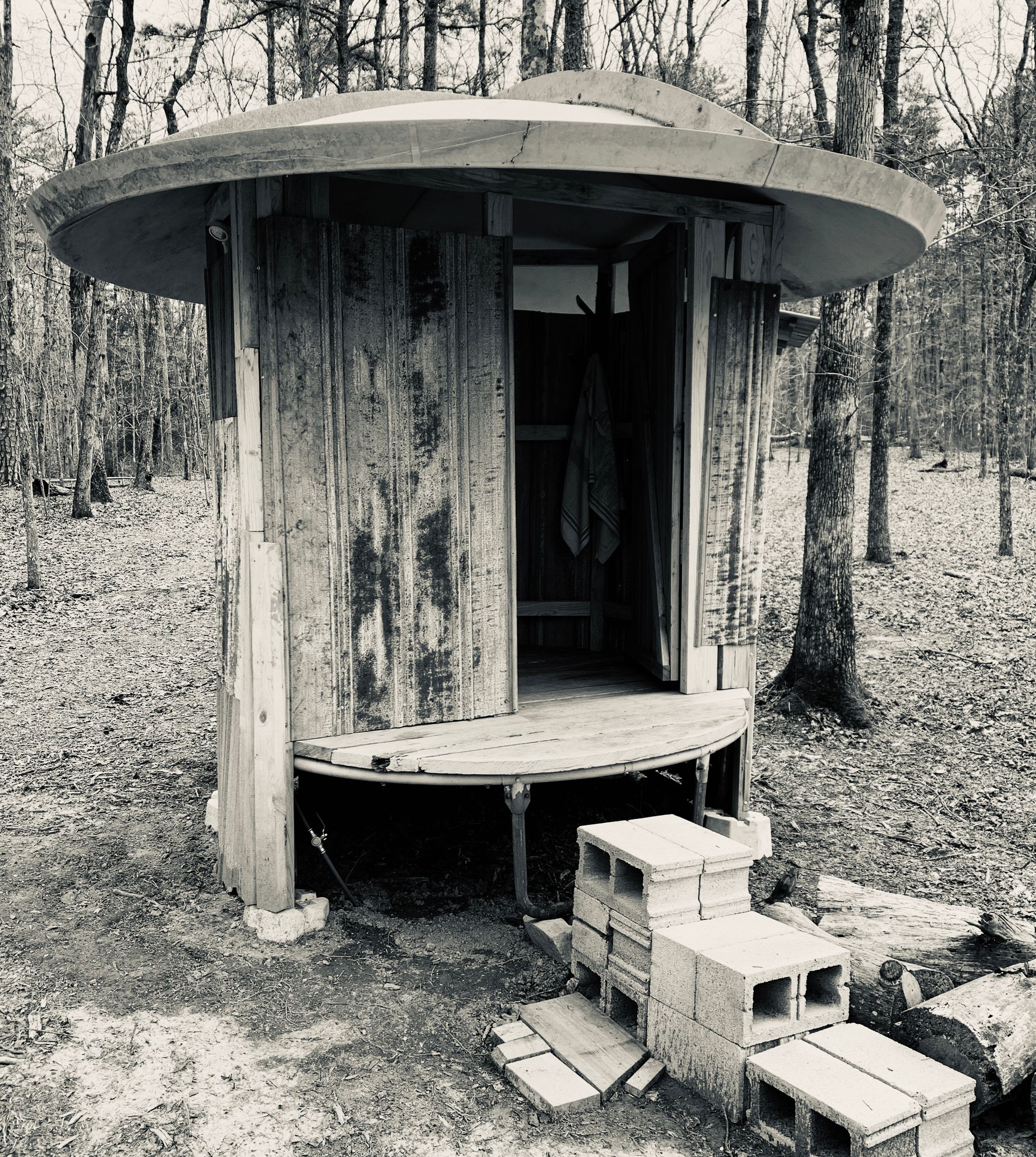 A black and white photo of a small wooden hut in the woods