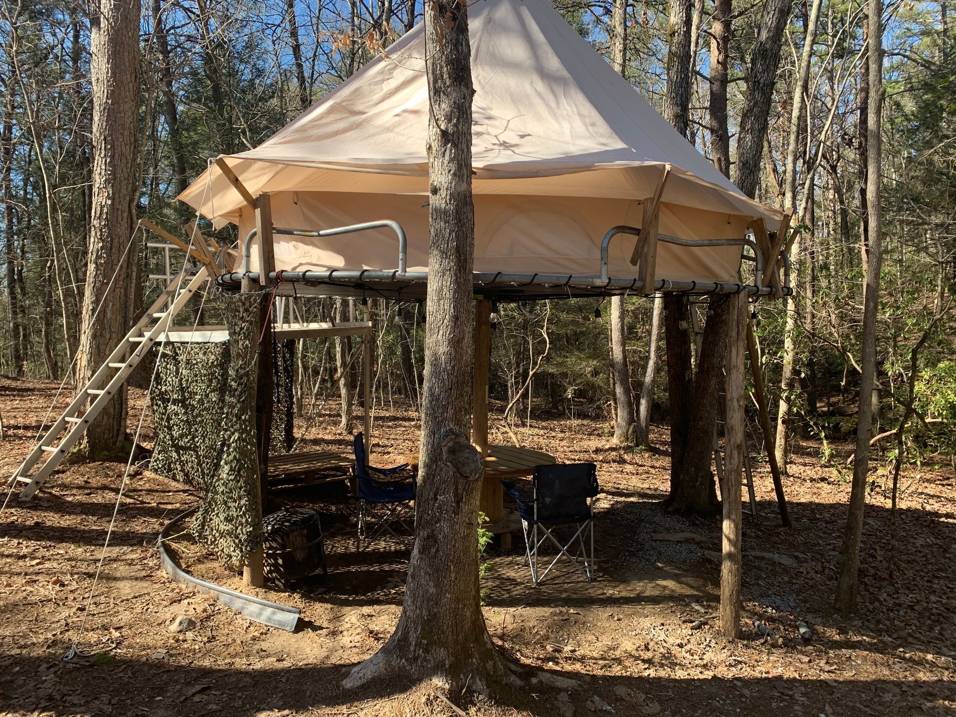 A tent is sitting on top of a wooden platform in the middle of a forest.