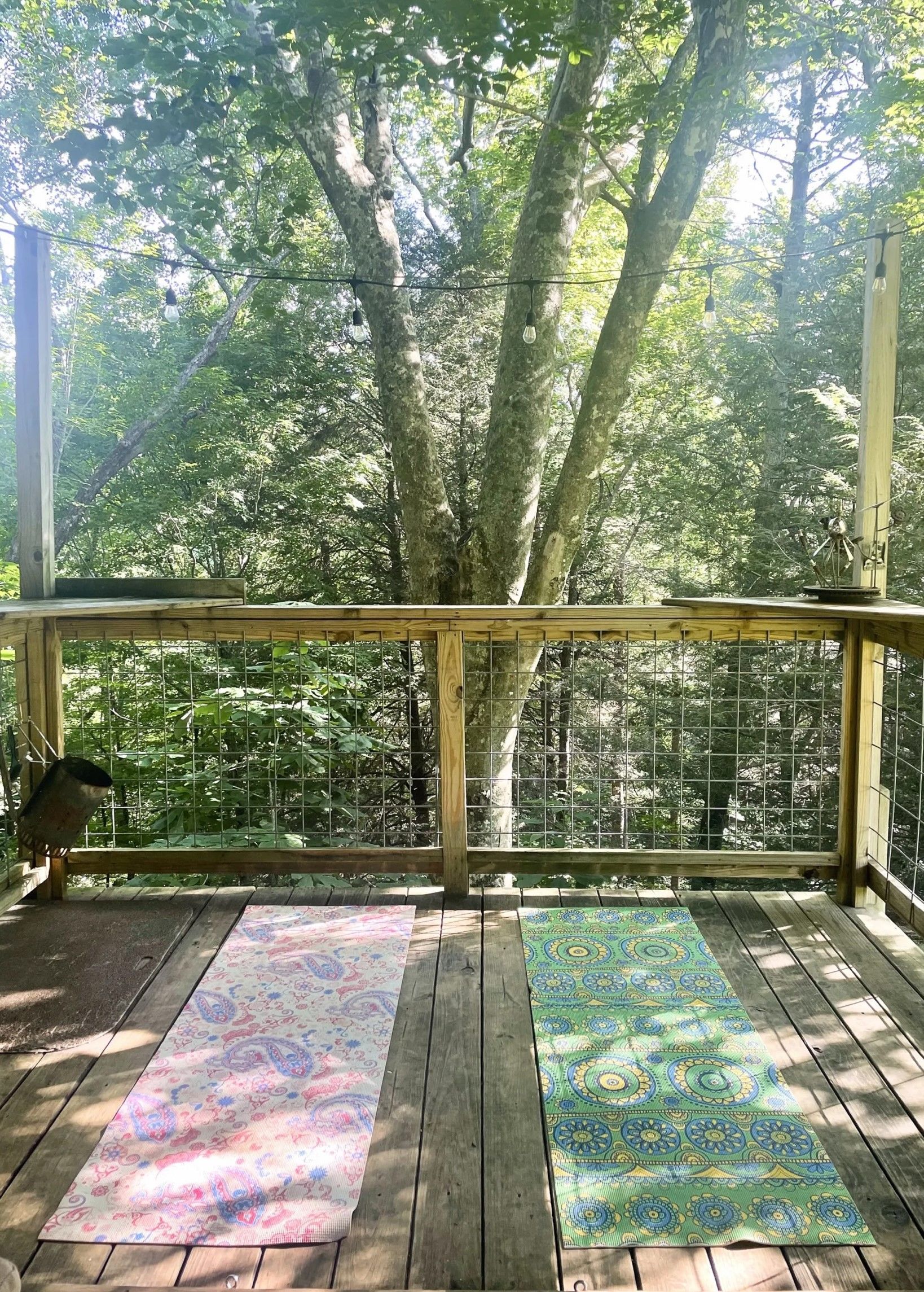 A yoga mat is sitting on a wooden deck next to a tree.