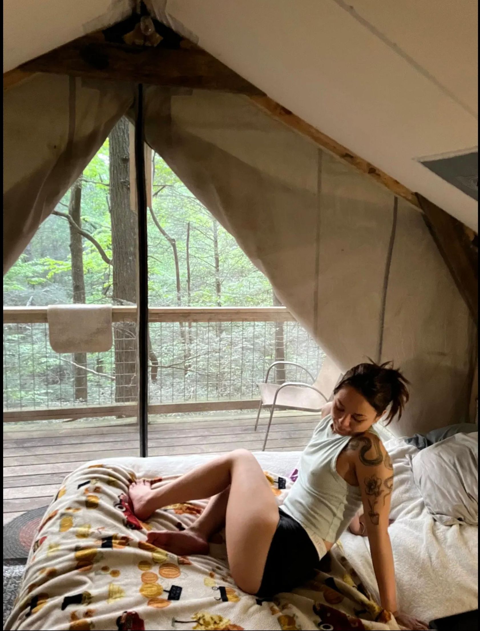 A woman is laying on a bed in a tent.