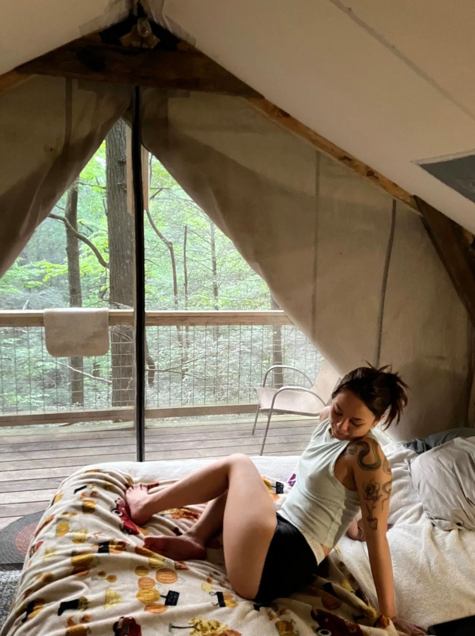 A woman is laying on a bed in a tent.