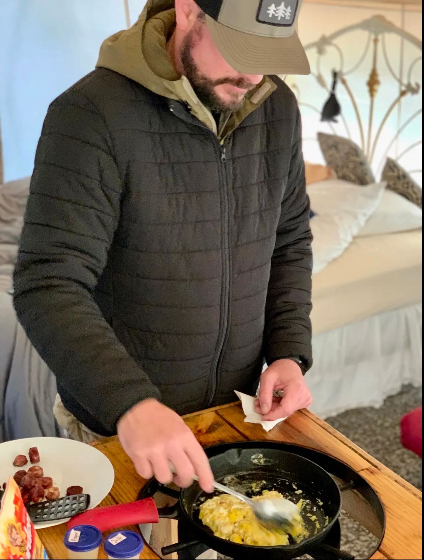 A man in a hat is cooking food in a frying pan