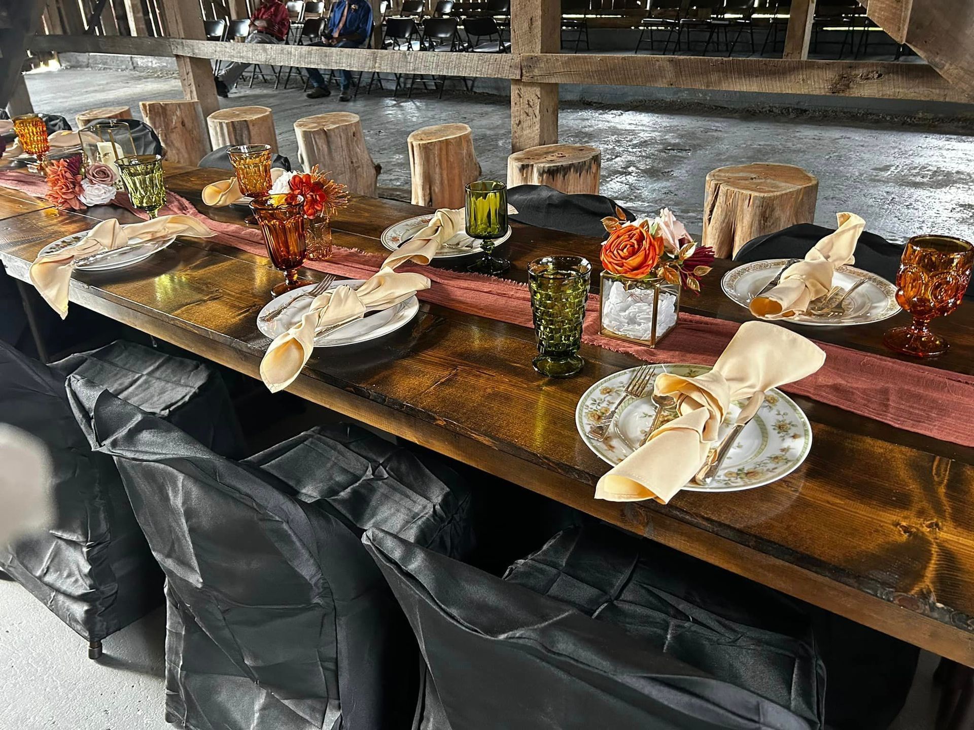 A long wooden table with plates , glasses , and napkins on it.
