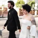 A bride and groom are walking down the street holding hands.