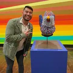 A man is standing next to a statue of a bird.