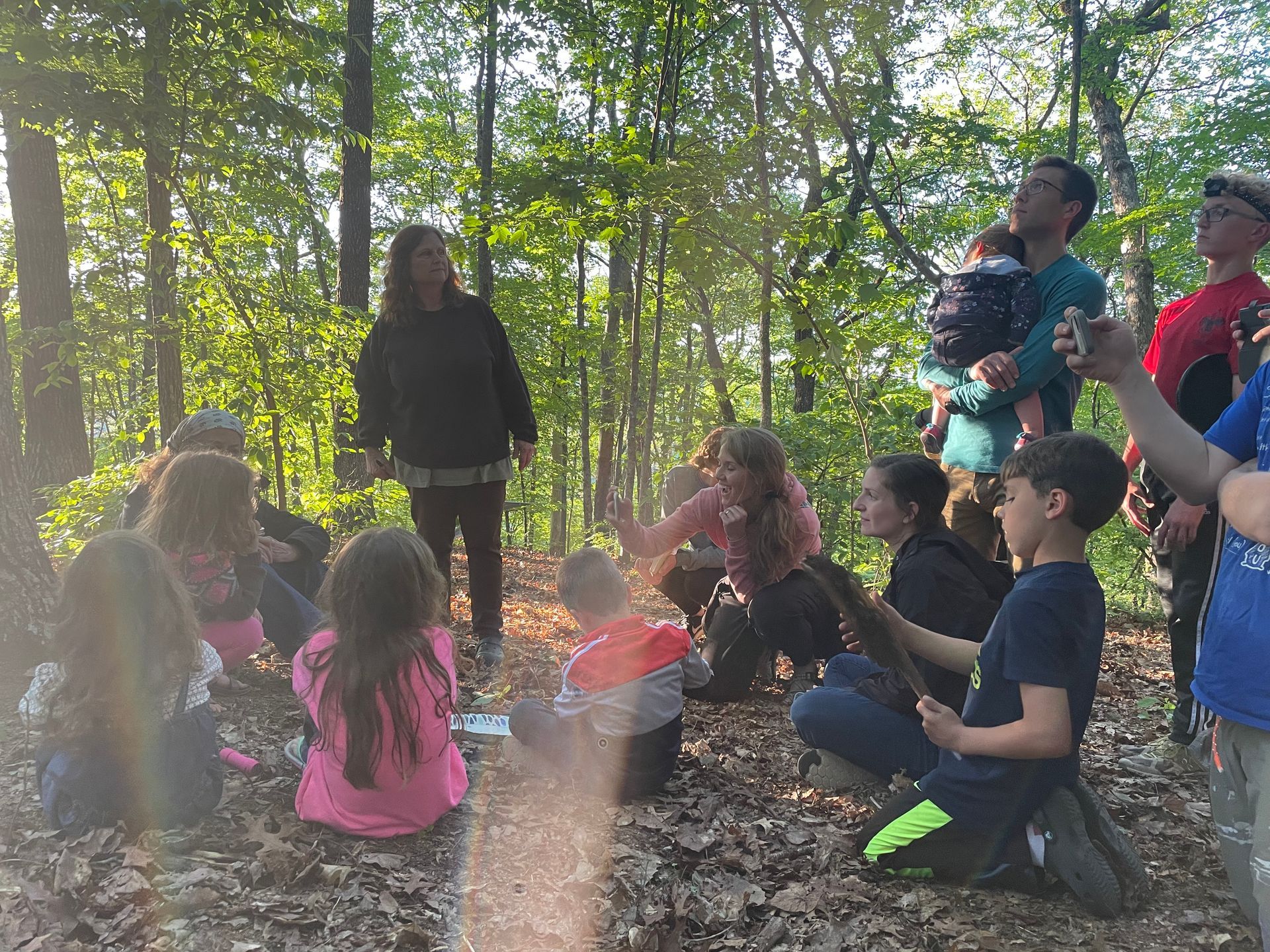 A group of people are sitting in a circle in the woods.