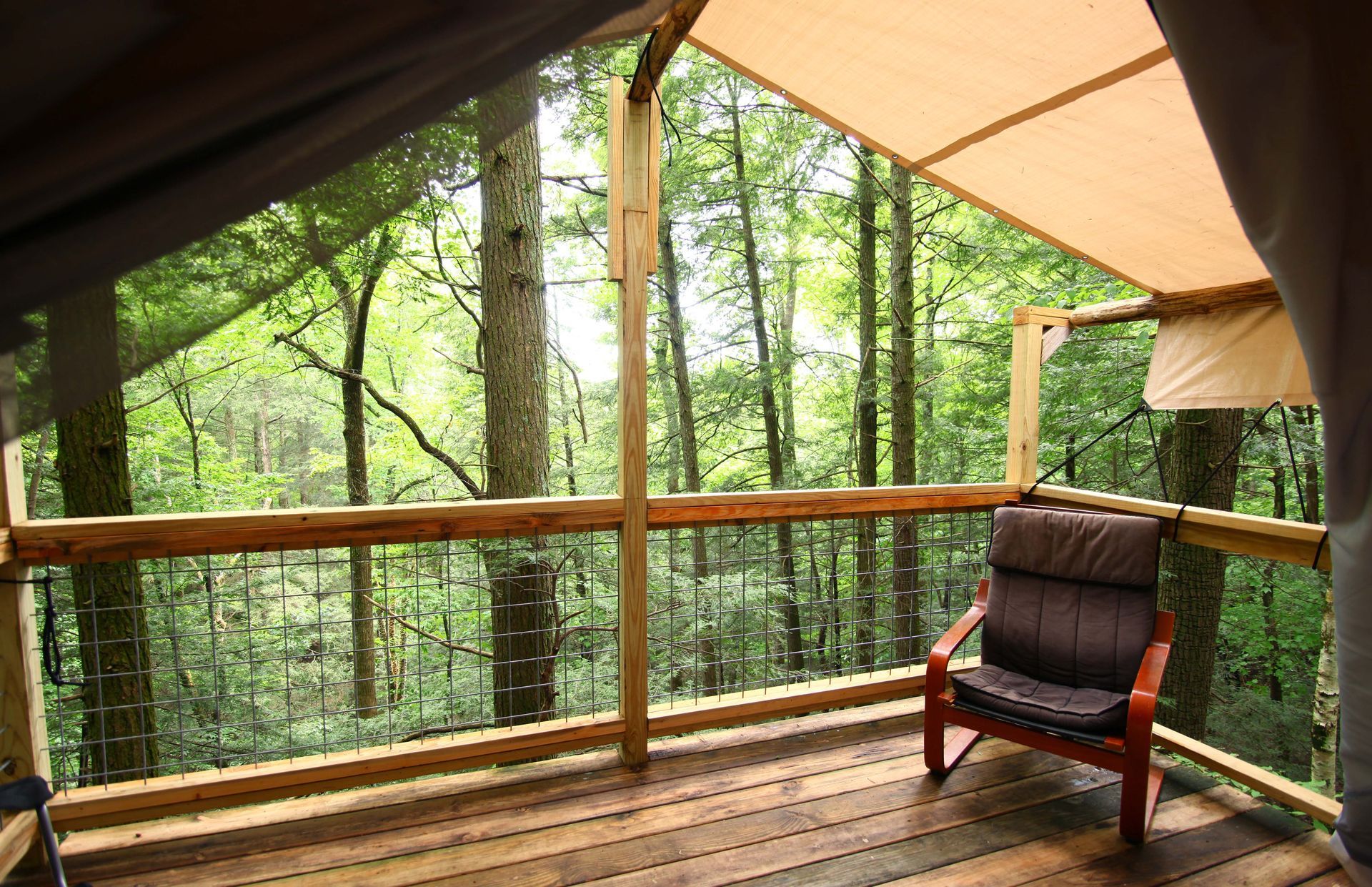 A wooden deck with a chair and trees in the background