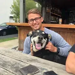 A man is holding a dog while sitting at a table.