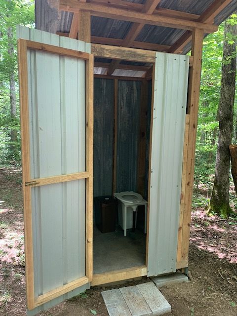 A shed with a toilet inside of it in the woods