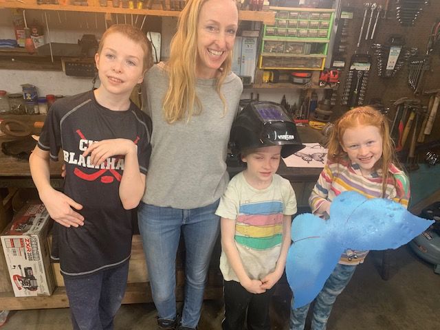 A woman and three children are posing for a picture in a garage.