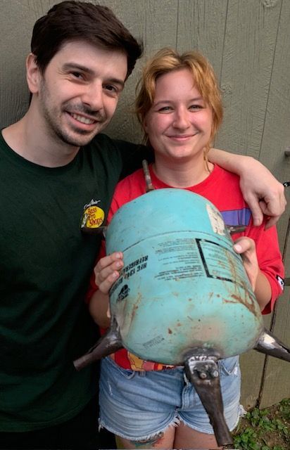 A man and a woman standing next to each other holding a blue tank
