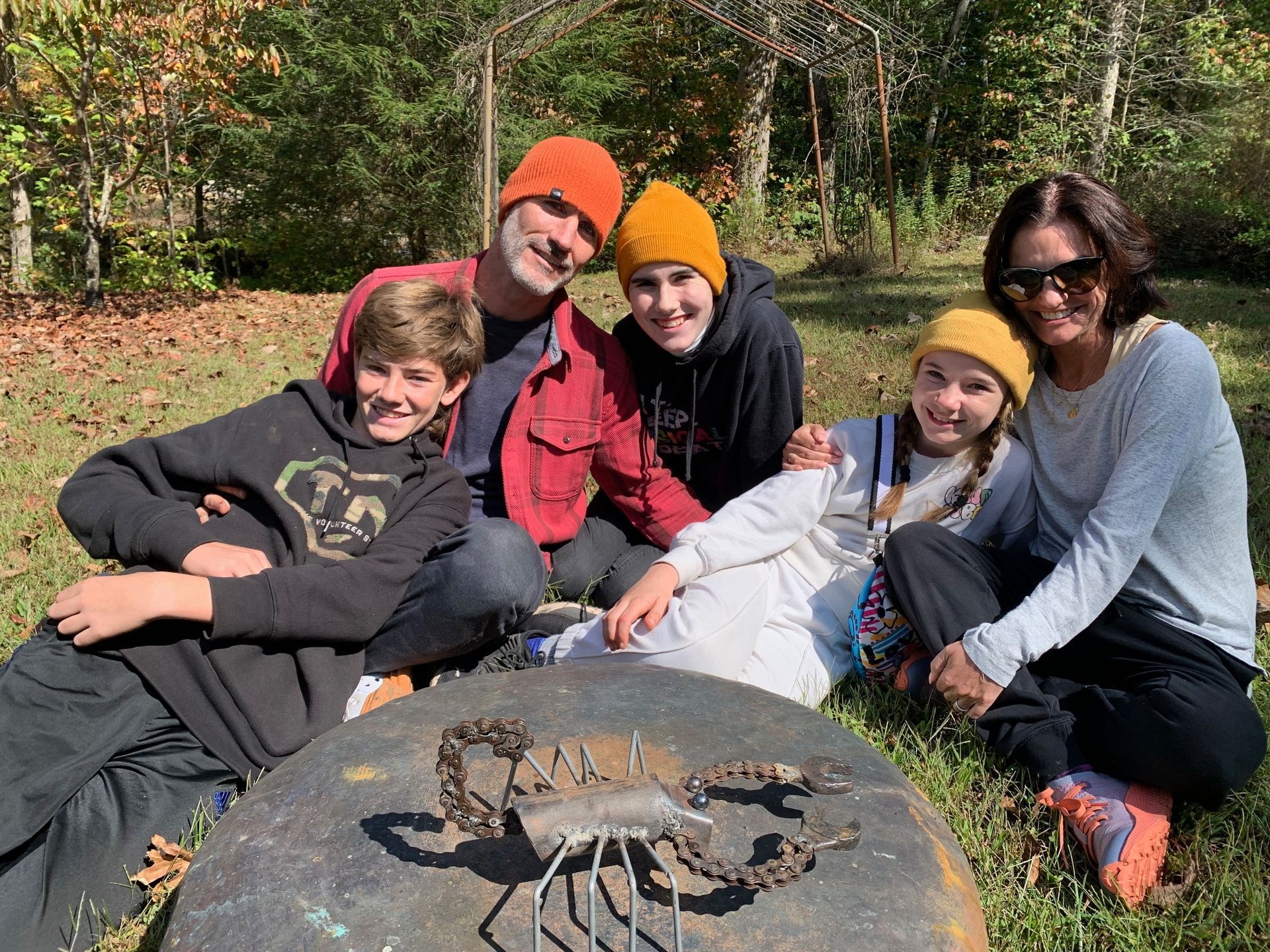A family is posing for a picture in front of a fire pit.