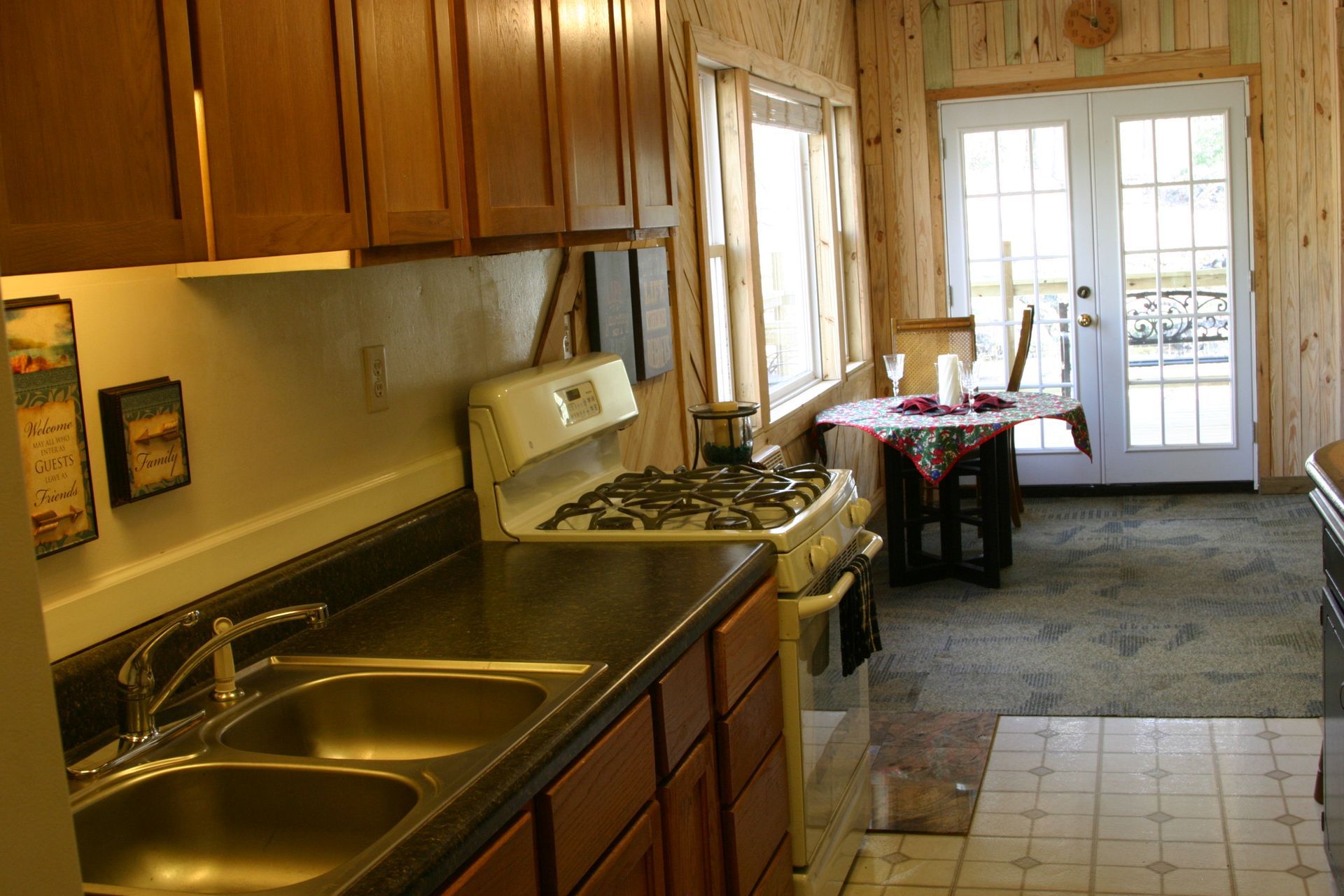 A kitchen with two sinks and a stove with a table in the background