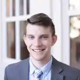 A young man in a suit and tie is smiling for the camera.