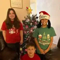 A group of children are standing in front of a christmas tree.