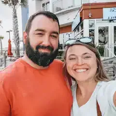 A man and a woman are posing for a picture in front of a building.