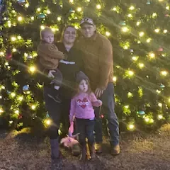 A group of children are standing in front of a christmas tree.