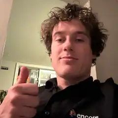 A man with curly hair is giving a thumbs up.