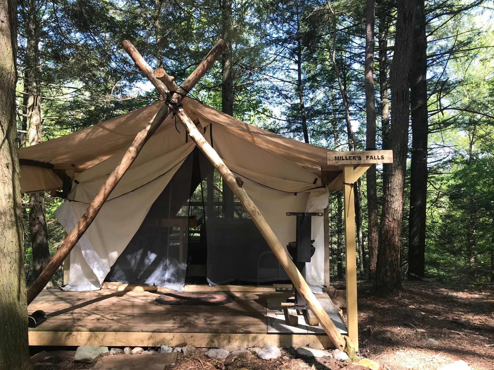 A tent is sitting on top of a wooden deck in the middle of a forest.