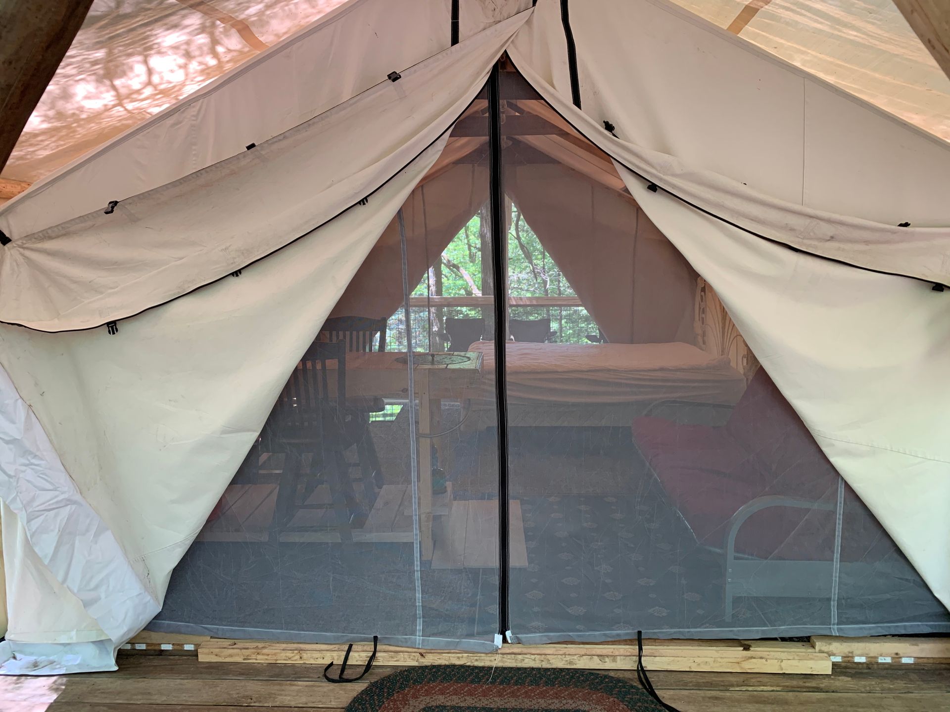 A tent with a mosquito net is sitting on a wooden deck.