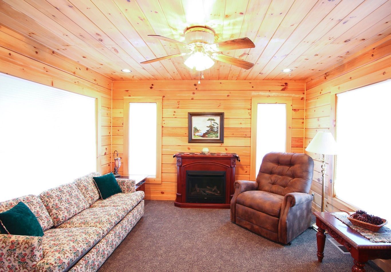 A living room with a couch , chair , fireplace and ceiling fan.