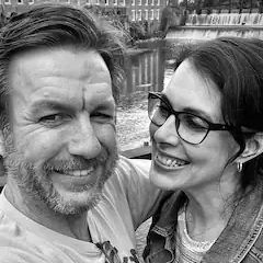 A man and a woman are smiling for a picture in a black and white photo.