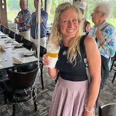 A woman is holding a glass of beer in a restaurant.