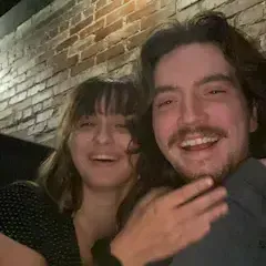 A man and a woman are posing for a picture in front of a brick wall.