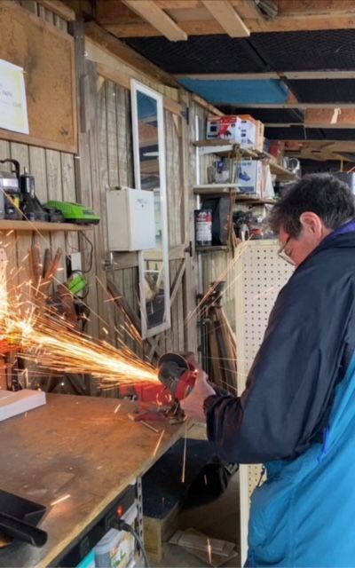 A man is using a grinder to cut a piece of metal