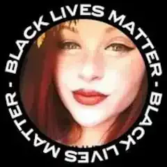 A woman with red hair is wearing a black lives matter shirt.