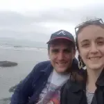 A man and a woman are posing for a picture on the beach.