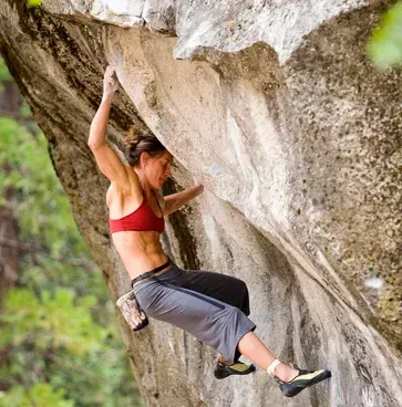 A woman in a red bra is climbing a rock