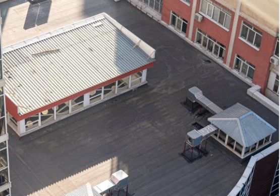 Overhead view of a building rooftop with air vents and a structure featuring a corrugated metal roof.