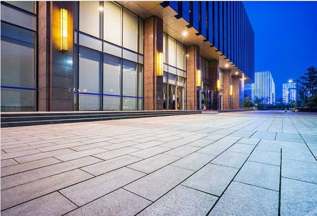 Modern office building exterior with tiled walkway at dusk.