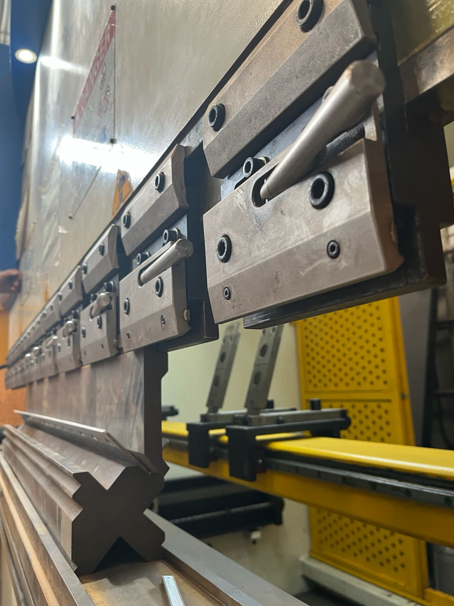 Prensa plegadora de chapa metálica con matrices superior e inferior, preparada para doblar chapas metálicas.