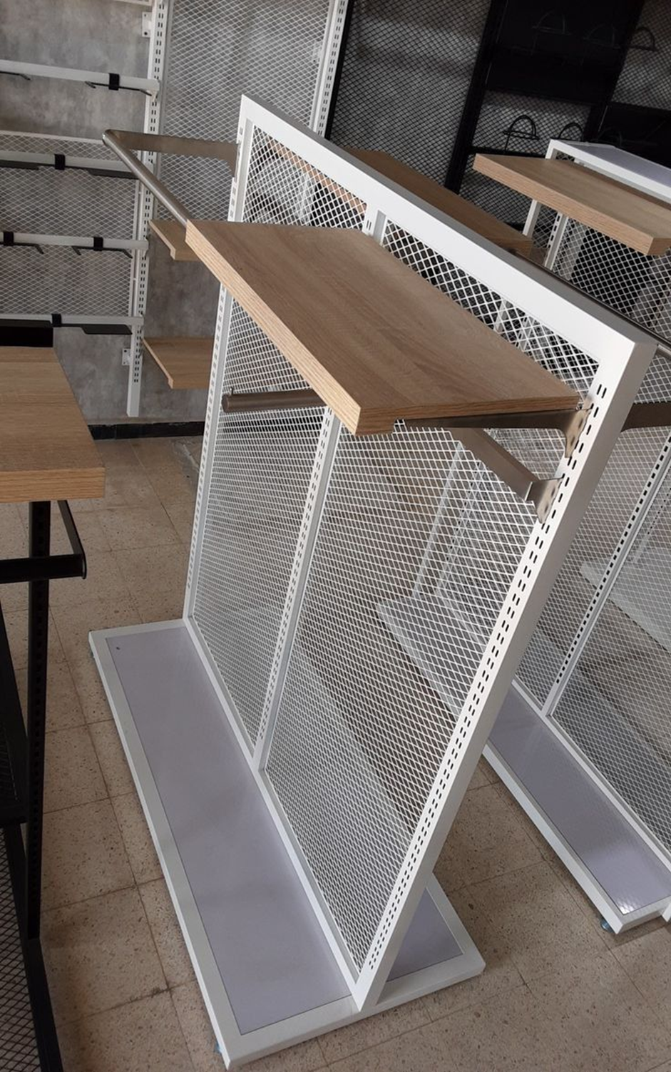 Expositor de metal blanco con estantes de madera y soporte de malla, para interior.