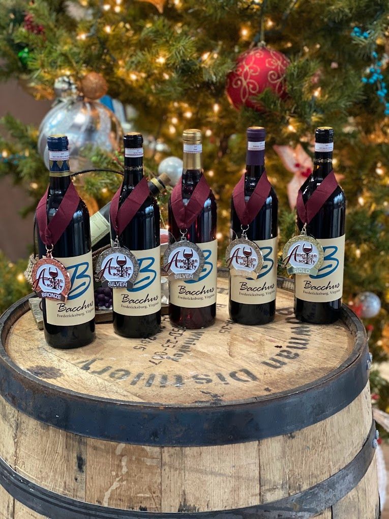 A group of wine bottles sitting on top of a wooden barrel in front of a christmas tree.
