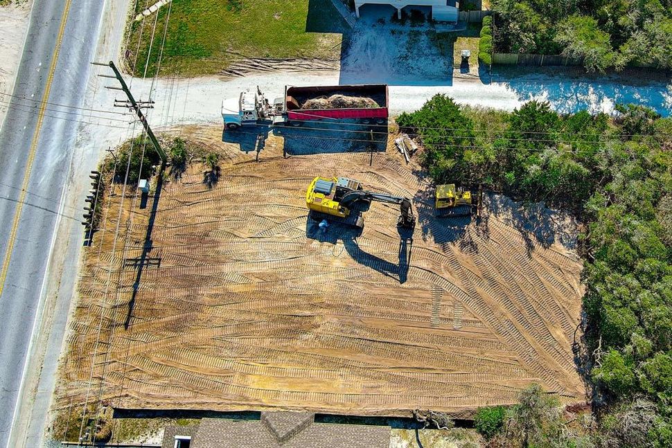An aerial view of a construction site with a house in the background.