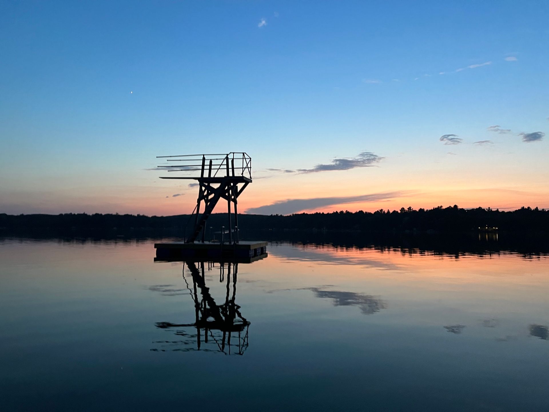 A diving platform in the middle of a lake at sunset