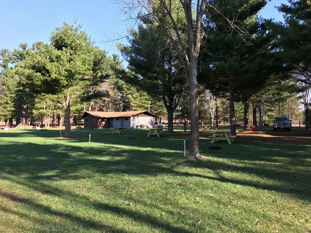 A picnic area with a shed and trees in the background.