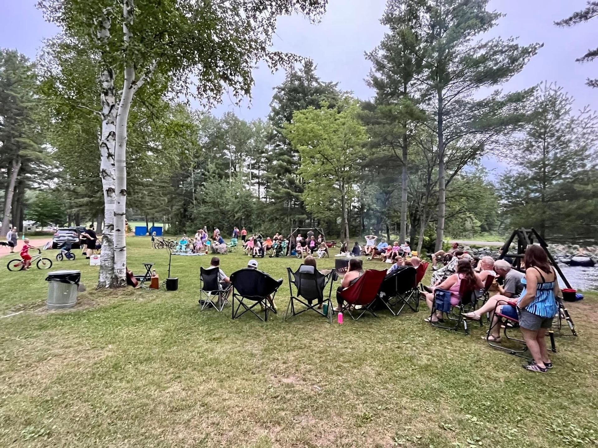 A group of people are sitting in chairs in a park.