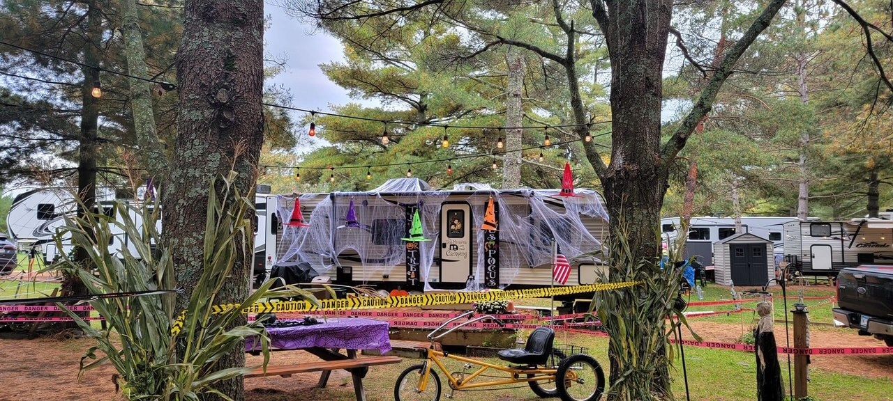 A rv is parked in a campground surrounded by trees.