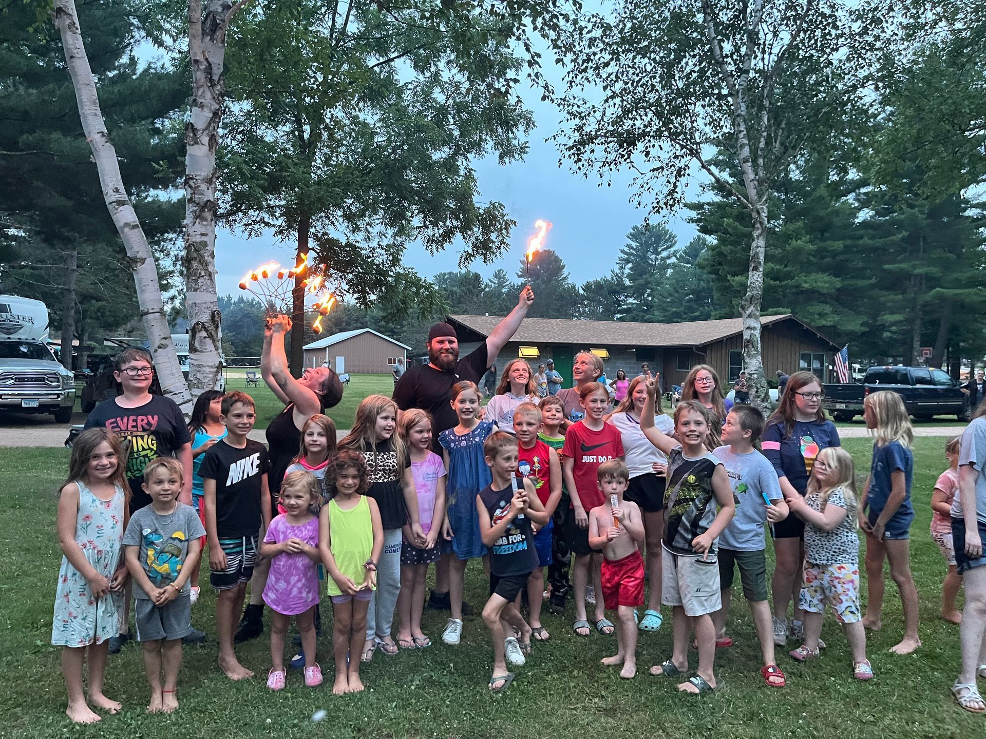 A group of children are standing in a field holding sparklers.