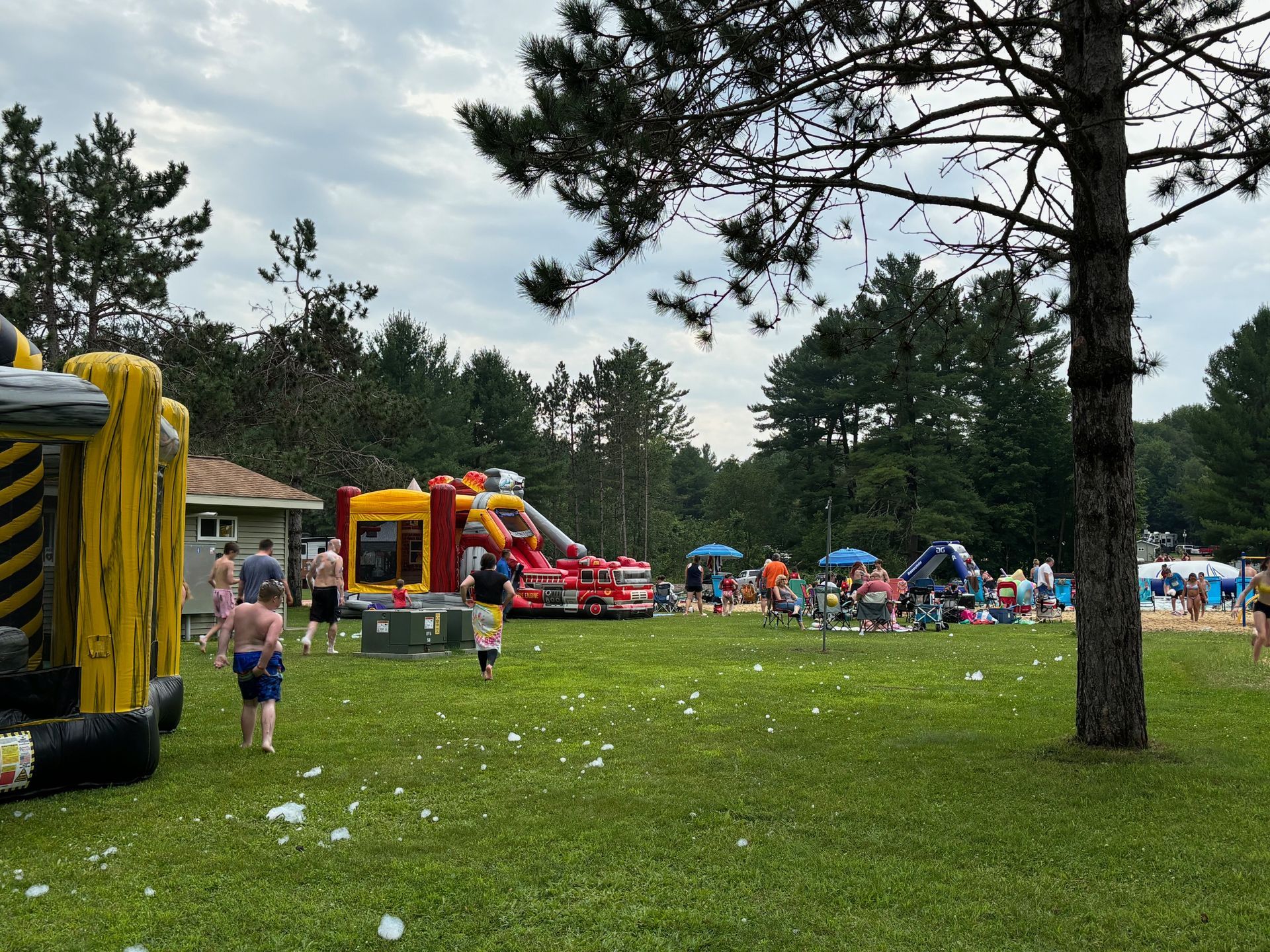 A group of people are playing in a park with bouncy houses and a slide.