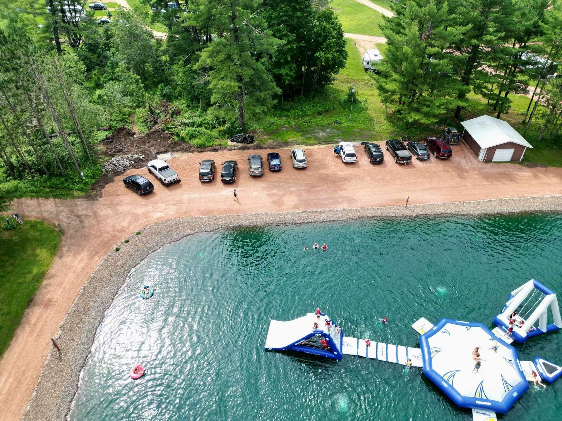 An aerial view of a lake with cars parked on the shore.