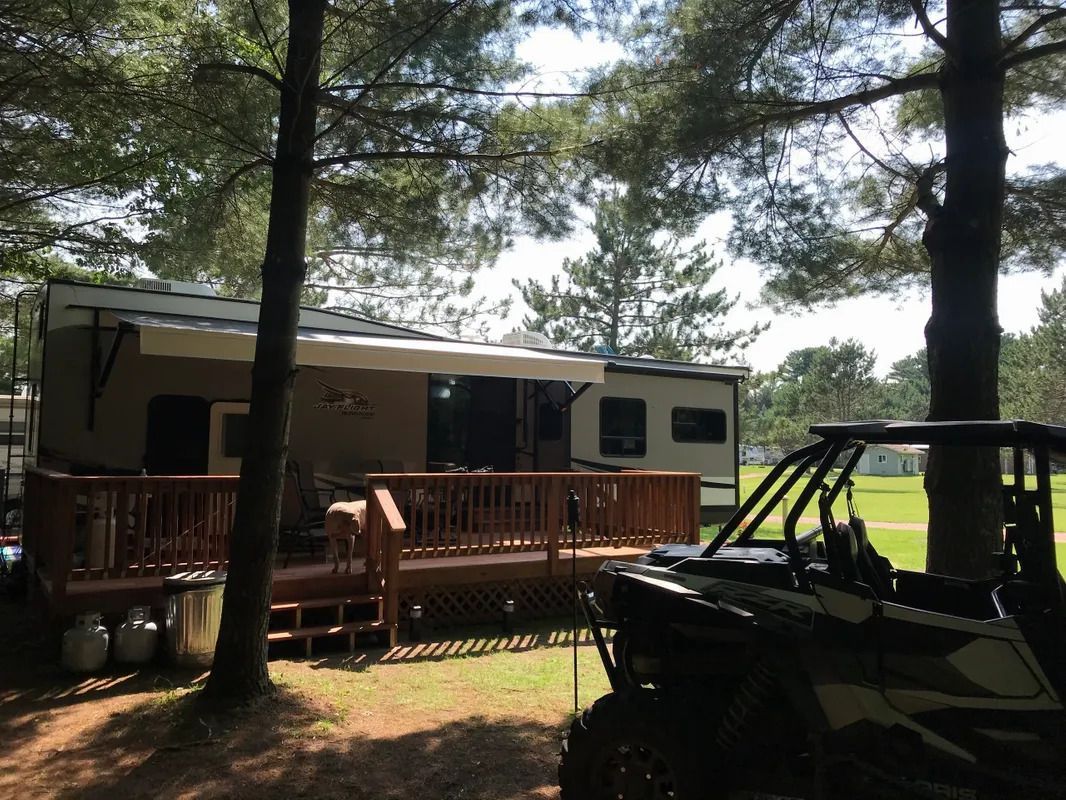 A trailer with a deck and a atv parked in front of it.