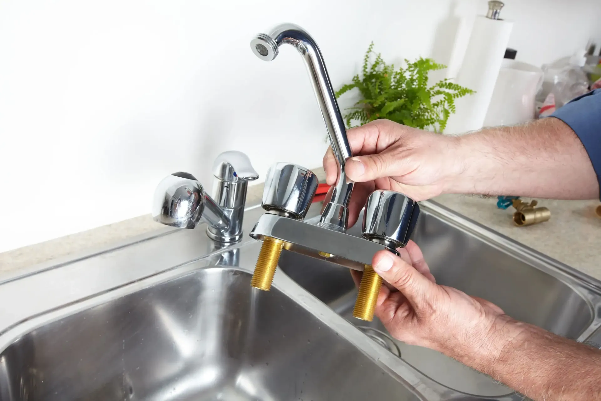 A man is fixing a faucet in a kitchen sink.