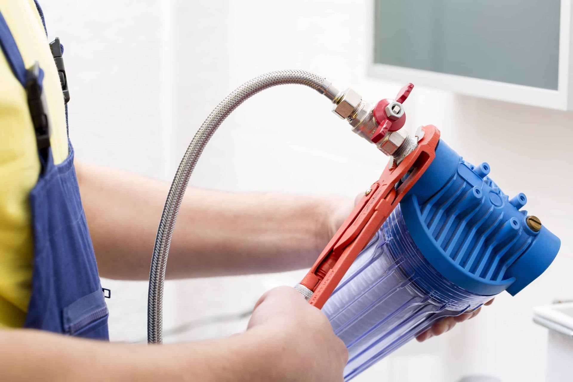 A plumber is fixing a water filter with a wrench.
