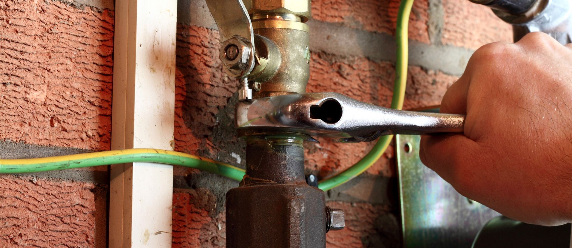 A person is fixing a pipe with a wrench.