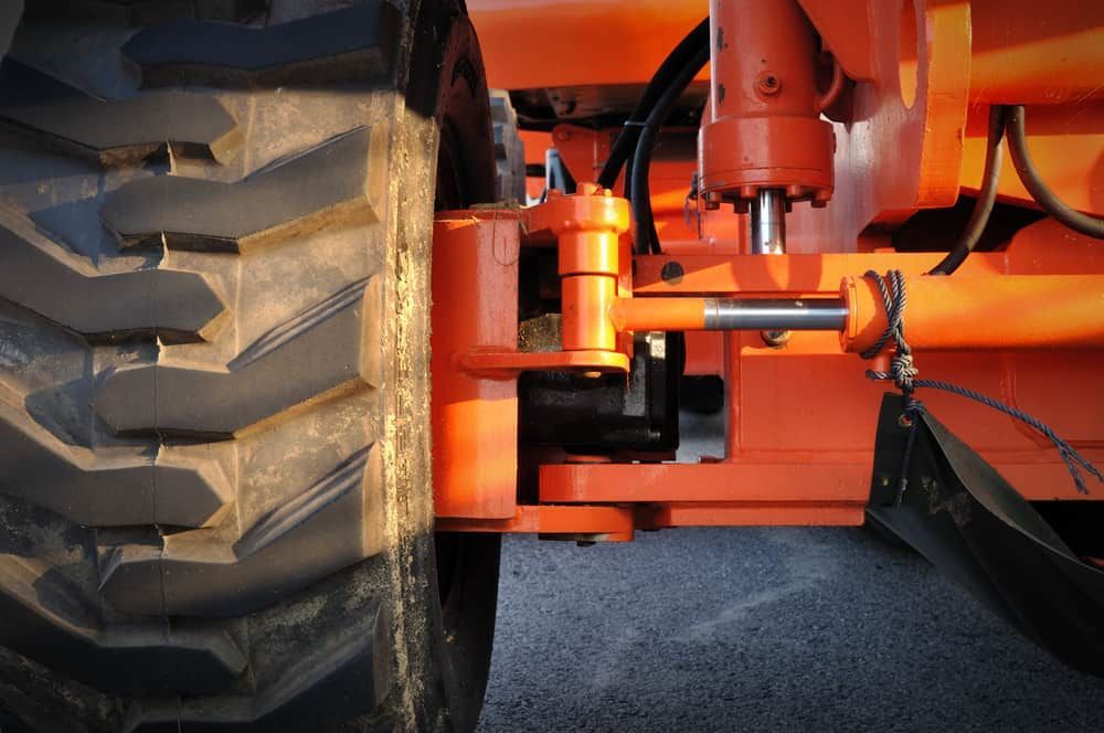 Close-up of an Orange Industrial Machine's Wheel and Suspension — Track N Back 4x4 In Atherton, QLD